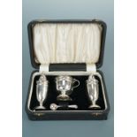 An Elizabeth II cased silver three piece cruet set, the pepper and salt pots of elongated ovoid