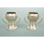 A pair of Edwardian miniature silver three-handled bowls, of geometric form, Goldsmiths and