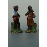 A pair of late 19th Century earthenware spill vases modelled as a young boy and girl wearing