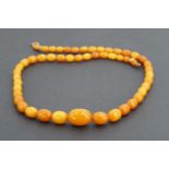 An antique butterscotch amber necklace of graded ovoid beads, 49 cm, largest bead 13 mm x 18 mm,