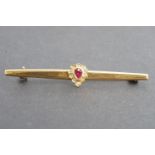 A 14ct gold, diamond and ruby bar brooch, with central pear cut ruby of approximately .30ct, rub set