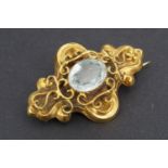 A Victorian flamboyant yellow metal brooch centred by a large aquamarine coloured stone, 4.5 cm x