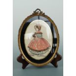 A 1920s Irish silkwork picture of a woman in 18th Century dress, in a verre eglomise mount and