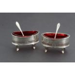 A pair of Georgian-influenced silver table salts and spoons, each of navette form, decorated with an
