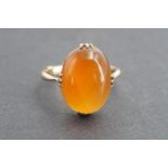 A carnelian and yellow metal dress ring, the cabochon carnelian held in a decorative claw-setting,