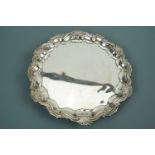 A George V silver card tray, with Chippendale and shell border, over three ball and claw feet,