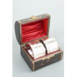 A cased pair of Victorian silver napkin rings, each of cylindrical form bearing readed and beaded