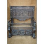 A late 19th Century Flemish style carved oak box settle, decorated in depiction of scenes from the