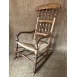 A Victorian rush-seated spindle-back beech rocking armchair