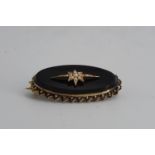 A Victorian mourning locket brooch, comprising a subtly concave oval French jet plaque centred by