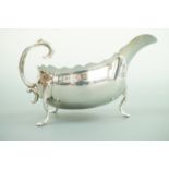 An Edwardian silver sauce boat, of helmet form, having a cusped rim, flying scroll handle and
