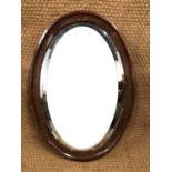 An oak framed oval bevel edged mirror, 85 x 59 cm