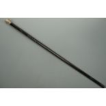 An antique carved ebony walking cane with white metal pommel, 81 cm