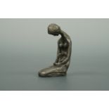 A small cast metal sculpture of a female nude, modelled kneeling in a contemplative prayer-like pose