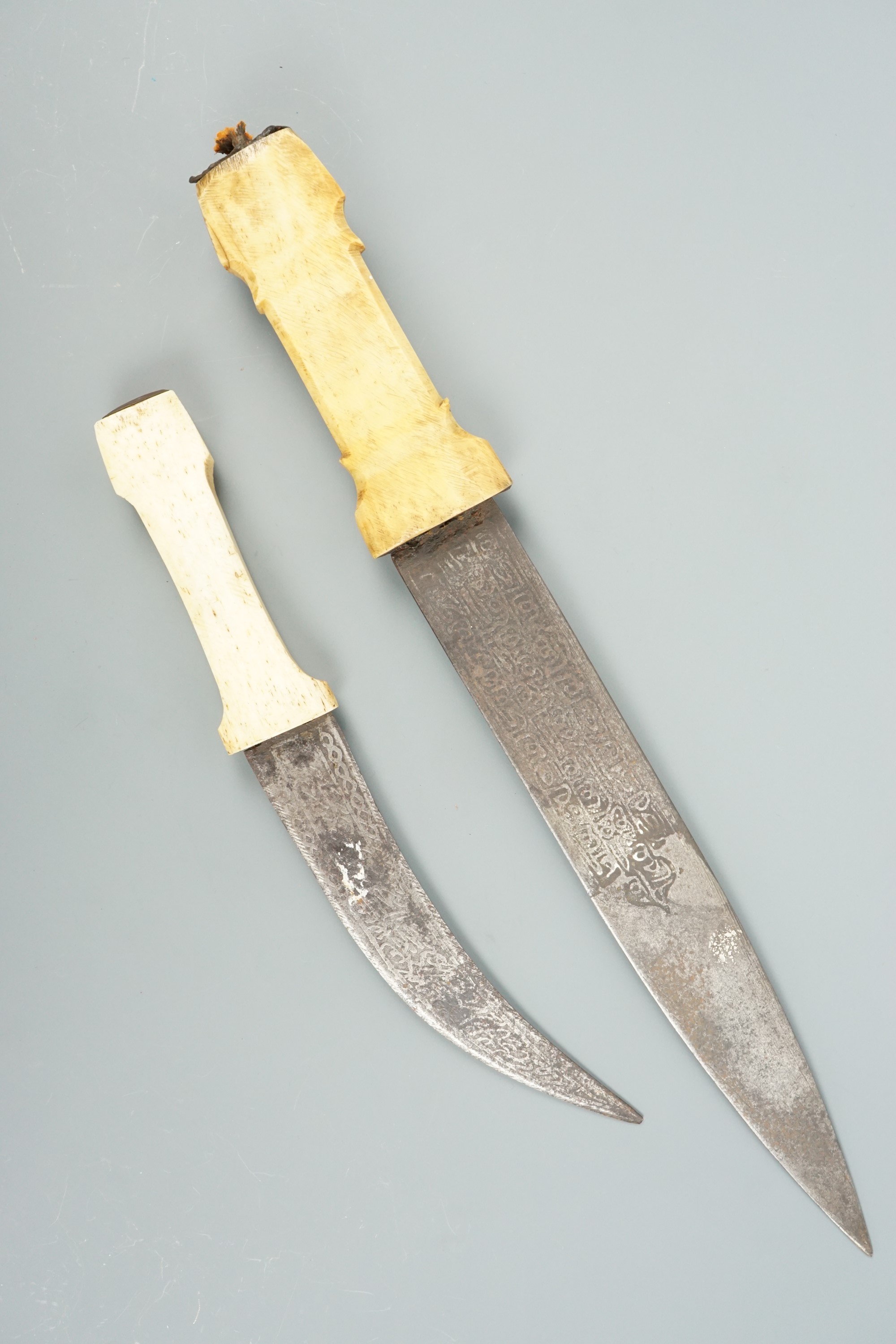 Two Middle Eastern bone-handled knives, having etched Islamic script on their blades