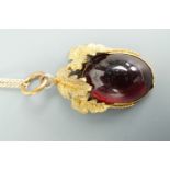 A vintage pendant modelled as a fruit and set with a garnet-coloured oval cabochon, on a yellow