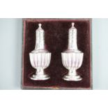 A cased pair of Victorian silver pepperettes, each of heavily-reeded shouldered-baluster form,