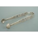 A pair of Georgian silver sugar tongs, with reticulated decoration, engraved with the initial 'E',