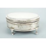 A George V silver ring / bijouterie box, of oval section, raised over four pad feet, the cover