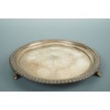 A George IV circular silver salver or waiter, having a gadrooned rim and raised on acanthus scroll