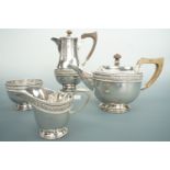 A George V late Arts and Crafts influenced silver four-piece tea service, each element planished and