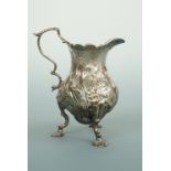 A George II silver cream jug, of baluster form, raised over three shell-hipped and volute feet,