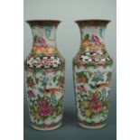 A pair of Qing Chinese Canton type famille-rose rouleau vases, decorated with figural scenes,