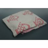 A pink and white patchwork quilt worked in a repeating basket design, approximately 200 x 170 cm,