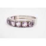 An amethyst and white metal hinged bangle, crown-set with nine circular (1 cm) stones, 58 x 51 mm