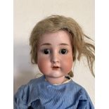 A large antique porcelain bisque headed doll, having sleeping brown glass eyes, blonde hair, and
