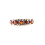 A five-stone garnet ring, the graded stones scroll-set on a yellow metal shank, N, 2.6 g