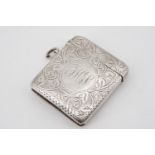 An Edwardian silver Vestas case of cushion form, foliate-scroll-engraved, the front centred by a