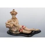 A contemporary ceramic figurine modelled as a young south Asian woman recumbent in exotic dress,