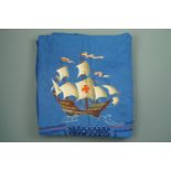 A large Second World War embroidered tablecloth bearing depictions of galleons and the names of