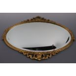 An ornate gilt oval mirror, 60 x 47 cm