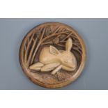 A Fisher Pottery buff-glazed earthenware plaque depicting a deer faun sleeping beneath an oak