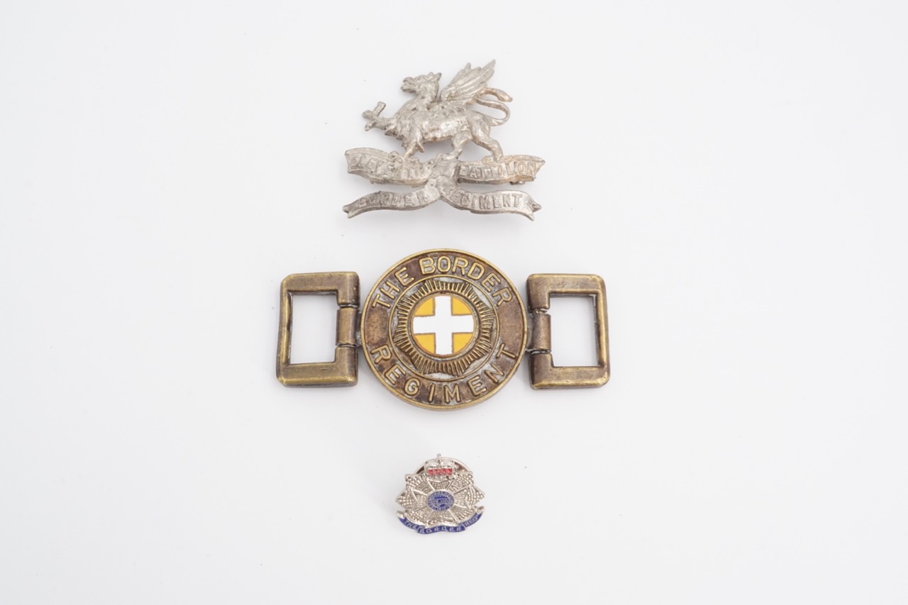 A Border Regiment buckle, lapel badge and reproduction cap badge