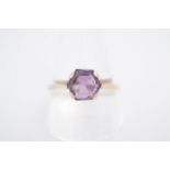 An amethyst solitaire ring, the 7 mm hexagon-cut stone set on a yellow metal shank, stamped 9 ct, T