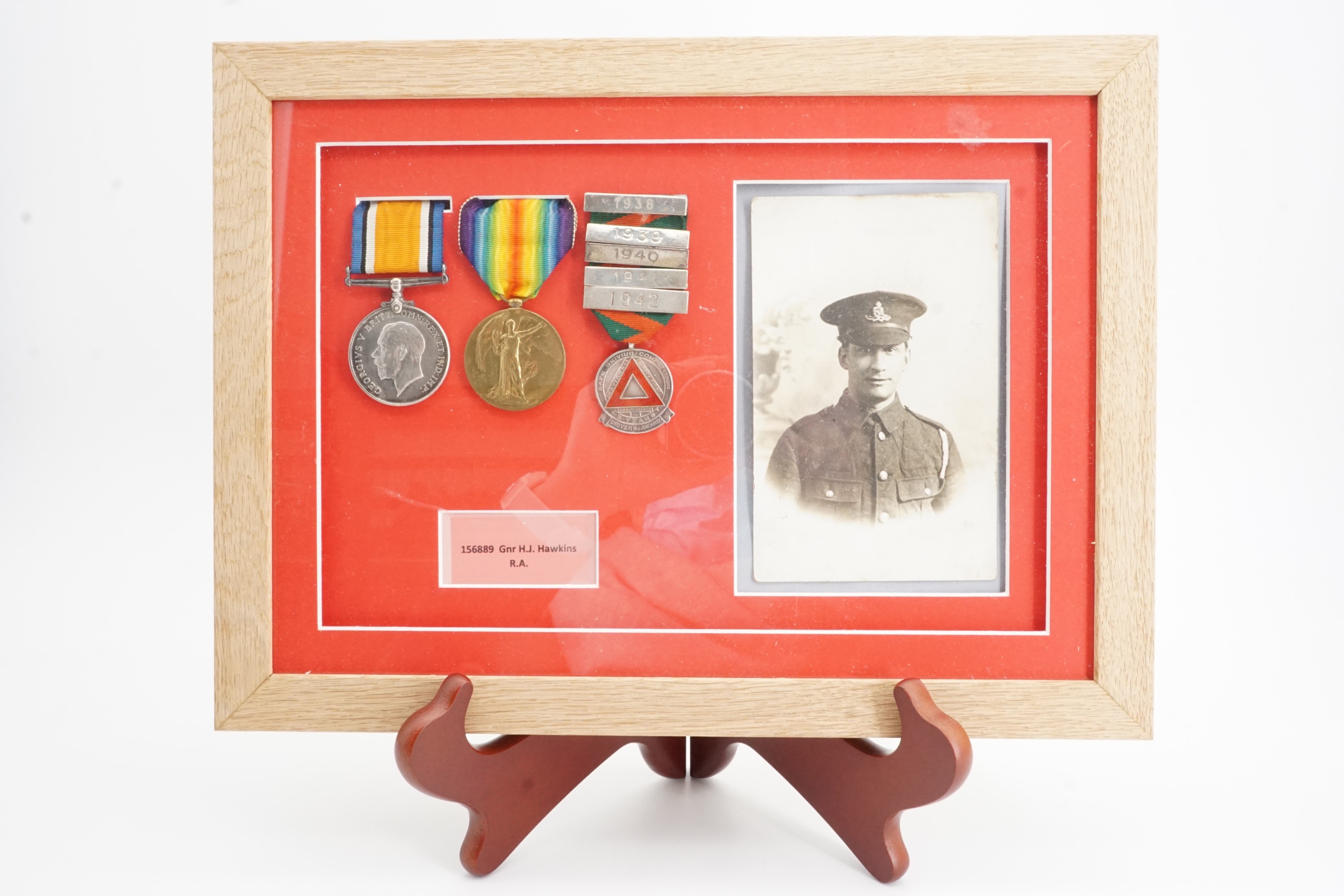 Framed British War and Victory medals together with a driving medal to 156889 Gnr H J Hawkins, RA