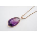 An amethyst and yellow metal pendant, the teardrop shaped stone (23 x 31 mm) bezel-set, together