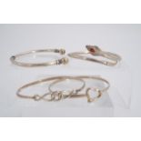 A white metal Celtic style torc bangle, a serpent bangle and two other silver bangles