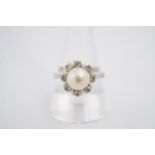 A flowerhead pearl and white stone dress ring, the pearl 7 mm, on a yellow metal shank, R