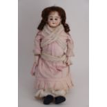 A late Victorian / Edwardian porcelain doll, having a bisque head with glass eyes and open mouth,