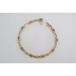 An emerald and yellow metal bracelet, comprising oval emeralds claw-set between small brilliants and