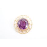 A purple sapphire brooch, the 16 mm stone bezel-set on a yellow metal open-work boss-form mount, 3