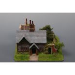 A hand-built scale model of a Victorian Lakeland two-storey pebble dashed cottage, with walled