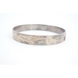An Elizabeth II patented silver hinged bangle, bearing wriggle-worked engraved decoration,