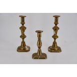 A pair of brass candlesticks, 25 cm high and a Georgian candlestick, 17 cm high