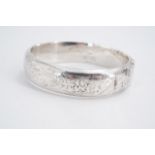 A 1950s silver hinged bangle, bearing engraved foliate decoration, 7 cm x 6 cm