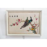 A Chinese silkwork picture depicting a peahen and peacock on a floral bough, framed under glass,